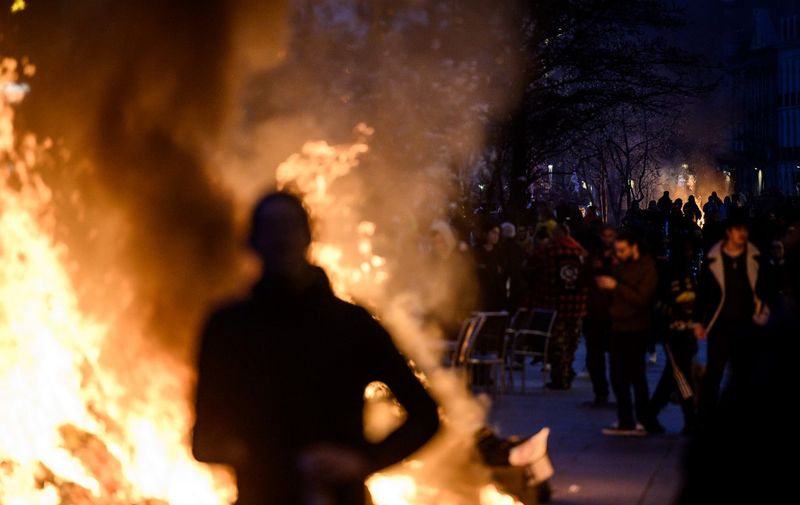 A protester is silhouetted by a bonfire during a demonstration after the French government pushed a pensions reform through parliament without a vote, using the article 49.3 of the constitution, in Nantes, western France, on March 16, 2023. - The French president on March 16 rammed a controversial pension reform through parliament without a vote, deploying a rarely used constitutional power that risks inflaming protests. The move was an admission that his government lacked a majority in the National Assembly to pass the legislation to raise the retirement age from 62 to 64. (Photo by LOIC VENANCE / AFP)