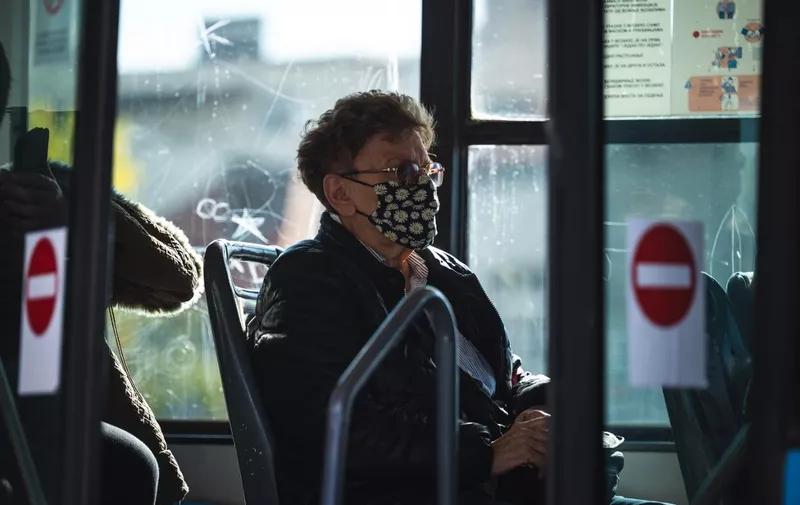 A woman wearing protective face mask sits in a bus in Belgrade on October 21, 2020. - As coronavirus cases rise both globally and in the region, Serbian government is tightening mask-wearing rules and restricting opening hours of bars and restaurants. (Photo by Andrej ISAKOVIC / AFP)