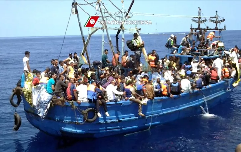 In this video grab released by the Italian Coast Guards (Guardia Costiera) on August 23, 2015 migrants wait on an overcrowded boat during a rescue operation off the coast of Libya as part of the Frontex-coordinated Operation Triton. Italy's coastguard coordinated the rescue of 4,400 migrants from boats in the Mediterranean in a single day on August 22, 2015, officials said. Saturday's total was thought to be the highest for a single day in recent years as calm conditions encouraged people smugglers to leave Libya with boats stuffed with as many paying passengers on board as possible. The coastguard said it had received distress calls from a total of 22 vessels, either inflatable dinghies or wooden former fishing boats -- all of them dangerously overcrowded and many of them lacking basic safety equipment. AFP PHOTO / HO
= RESTRICTED TO EDITORIAL USE - MANDATORY CREDIT "AFP PHOTO / GUARDIA COSTIERA" - NO MARKETING NO ADVERTISING CAMPAIGNS - DISTRIBUTED AS A SERVICE TO CLIENTS =
