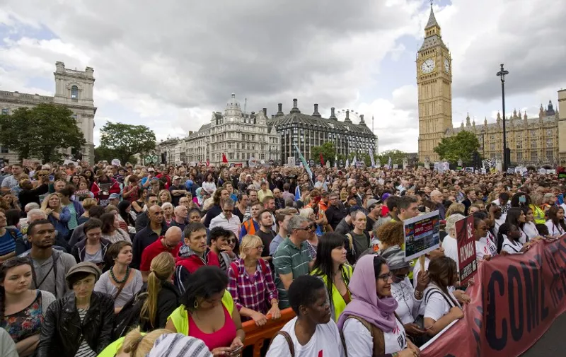 Demonstrators hold placards as pass the Houses of Parliament during a pro-refugee rally in central London on September 12, 2015. Tens of thousands of Europeans rallied urging solidarity with the huge numbers of refugees entering the continent, as Hungary's populist premier said leaders were "in a dream world" about the dangers posed by the influx. In London, one of dozens of events planned across Europe, tens of thousands of people marched brandishing placards reading "Open the Borders", an AFP journalist said, while in Copenhagen some 30,000 took to the streets, according to police.  AFP PHOTO / JUSTIN TALLIS