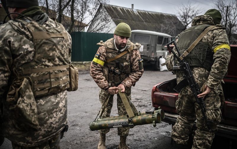 Ukrainian soldiers unload weapons from the trunk of an old car, northeast of Kyiv on March 3, 2022. - A Ukrainian negotiator headed for ceasefire talks with Russia said on March 3, 2022, that his objective was securing humanitarian corridors, as Russian troops advance one week into their invasion  of the Ukraine. (Photo by Aris Messinis / AFP)