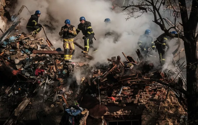 Ukrainian firefighters works on a destroyed building after a drone attack in Kyiv on October 17, 2022, amid the Russian invasion of Ukraine. - Ukraine officials said on October 17, 2022 that the capital Kyiv had been struck four times in an early morning Russian attack with Iranian drones that damaged a residential building and targeted the central train station. (Photo by Yasuyoshi CHIBA / AFP)
