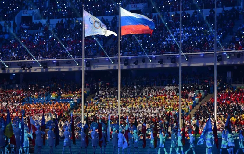 (FILES) This file photo taken on February 23, 2014 shows an Olympic Games flag and a Russian flag waving during the closing ceremony of the winter Olympics in Sotchi.
Russia operated a state-dictated doping system during the 2014 Sochi Winter Olympics and other events, an independent investigator said today in a report likely to lead to demands for Russia to be completely banned from the Rio Games. / AFP PHOTO / KIRILL KUDRYAVTSEV