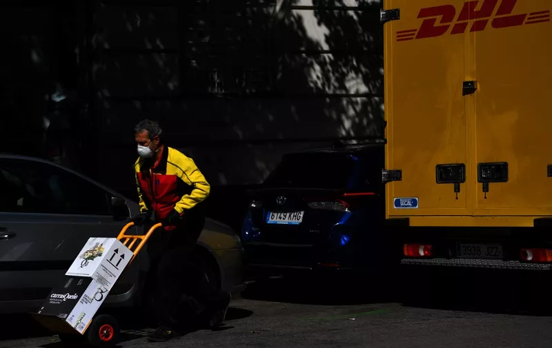 A DHL employee delivers boxes in Madrid on April 2, 2020 amid a national lockdown to fight the spread of the COVID-19 coronavirus. - The coronavirus death toll in Spain surged past 10,000 after a record 950 deaths in 24 hours, with the number of confirmed cases passing the 110,000 mark, the government said. (Photo by GABRIEL BOUYS / AFP)