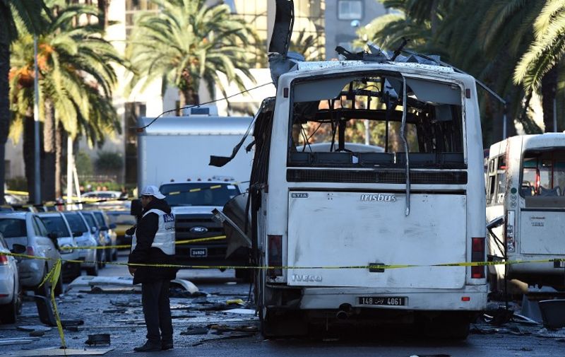 Tunisian forensic police inspect the wreckage of a bus in the aftermath of a bomb attack on the vehicle which was transporting Tunisia's presidential guard in central Tunis on November 25, 2015. Tunisia's President Beji Caid Essebsi declared a nationwide state of emergency and a curfew in the capital after a bomb attack on the presidential guard bus killed at least 12 people. AFP PHOTO / FETHI BELAID / AFP / FETHI BELAID