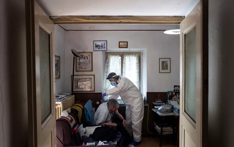 Doctor Annalisa Giordano of the USCA special care unit of ASL (local health center) of Cuneo, visits Don Ruggero Massimino, an elderly priest infected with the Covid-19 in Festiona, in the Stura di Demonte Valley, near Cuneo, north-western Italy on March 31, 2021. - Don Fabrizio Della Bella is a young priest that continue to visit his faithfuls in their homes, including those infected of Covid-19. He gives the host, confesses, and gives religious support. He was infected of Covid 19 the last summer and was admitted to the hospital for 20 days. (Photo by MARCO BERTORELLO / AFP)