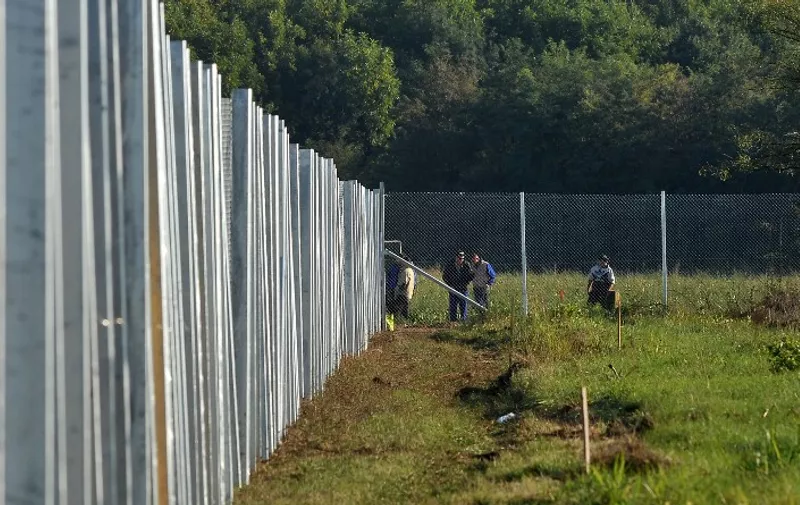 Hungarian soldiers and workers are seen as they continue the construction work of a steel fence near the official border crossing at the Croatian-Hungarian border between the villages of Baranjsko Petrovo Selo, Croatia, and Beremend, Hungary, on September 22, 2015. The fence system including chicken wire and barb-wire is in place at the border area to close the official border crossing in village of Beremend thus preventing further influx of Middle-Eastern migrants into Hungary. Hungary's parliament gave on September 21 the army and police sweeping new powers to keep migrants out as populist Prime Minister Viktor Orban warned that Europe was being "overrun". AFP PHOTO / ELVIS BARUKCIC