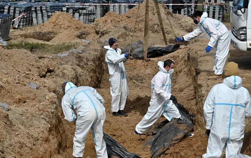 Workers exhume bodies from a mass grave in Bucha, north-west of Kyiv, on April 14, 2022. - French gendarmes and forensic doctors have arrived in Ukraine to help investigate the discovery of scores of bodies in civilian clothing scattered in Bucha and other towns around Kyiv after Russia's withdrawal from the region. Ukraine says it has discovered 1,222 bodies in Bucha and other towns. (Photo by Sergei SUPINSKY / AFP)