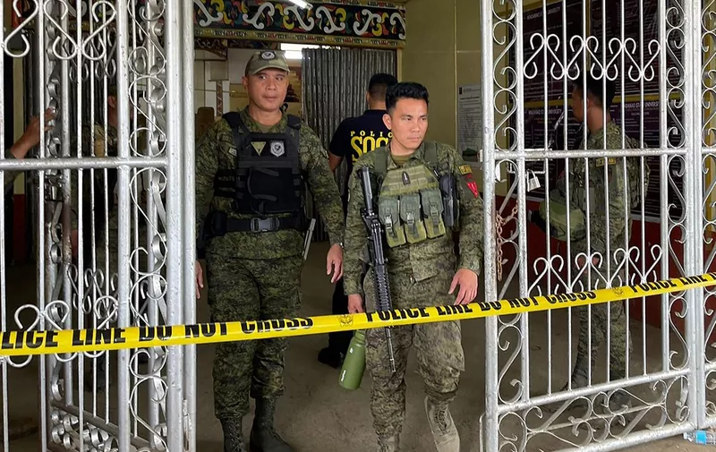 Military personnel stand guard at the entrance of a gymnasium while police investigators look for evidence after a bomb attack at Mindanao State University in Marawi, Lanao del sur province on December 3, 2023. At least three people were killed and seven wounded in a bomb attack on a Catholic mass in the insurgency-plagued southern Philippines on December 3, officials said. (Photo by Merlyn MANOS / AFP)