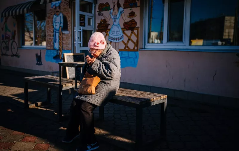 An elderly woman looks at her phone in the city of Kherson on December 31, 2022, amid the Russian invasion of Ukraine. (Photo by Dimitar DILKOFF / AFP)