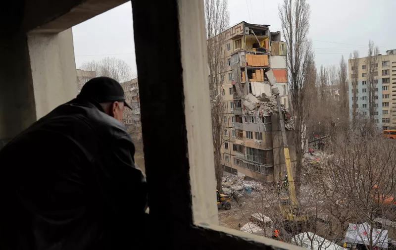 A local resident watches rescue works at the site of a heavily damaged multi-story apartment building, following a Russian drone attack, in Odesa, on March 2, 2024. (Photo by Oleksandr GIMANOV / AFP)