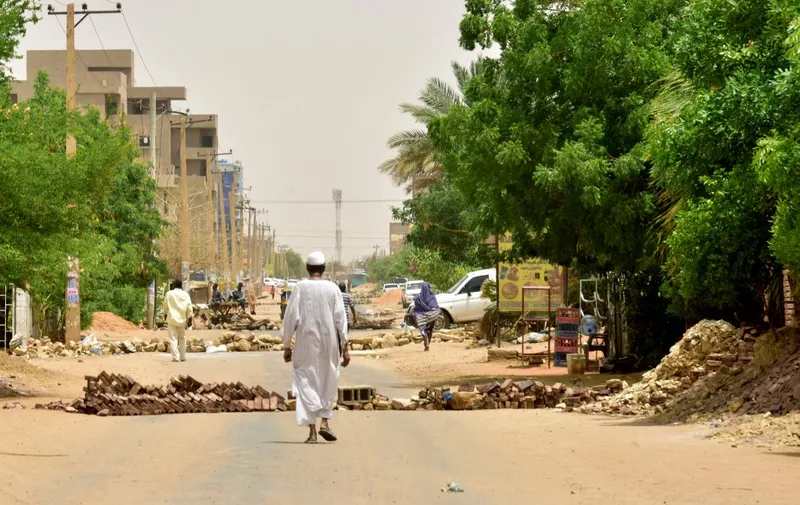 Sudanese residents walk past barricades in Khartoum on June 9, 2019. - Sudanese police fired tear gas on June 9 at protesters taking part in the first day of a civil disobedience campaign, called in the wake of a deadly crackdown on demonstrators. Protesters gathered tyres, tree trunks and rocks to build new roadblocks in Khartoum's northern Bahari district, a witness told AFP, but riot police swiftly moved in and fired tear gas at them. (Photo by - / AFP)