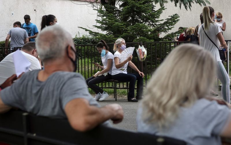 People wearing face masks wait for a health check in front of a COVID-19 medical centre in Belgrade on July 2, 2020. - Serbia on July 2, 2020 restricted gatherings of more than five people in towns hit by a spike of coronavirus cases. After reining in its first outbreak of COVID-19 in early May, the Balkan state is now reporting a second surge with around 250 cases daily this week compared to around 50 or less a month ago. The new clusters came after Serbia shed its lockdown measures to allow sporting events and national elections to go ahead in June. (Photo by Oliver BUNIC / AFP)