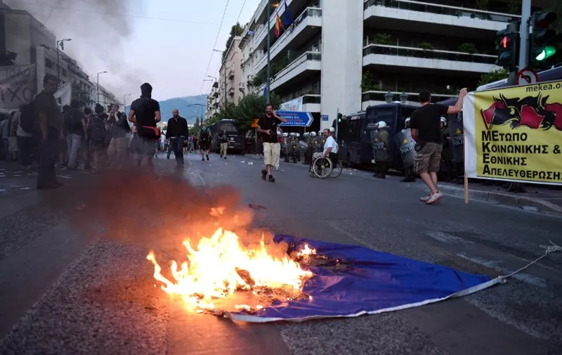 TOPSHOTS
Anti-EU protesters burn an EU flag outside the European Comission offices in Athens on July 2, 2015. Greece's government and international creditors raised the stakes on July 2 over a weekend referendum seen as decisive for the nearly insolvent EU country's political and financial future. While Prime Minister Alexis Tsipras has urged Greeks to vote 'No' to the austerity measures demanded by international creditors, opposition parties including the centre-right New Democracy are campaigning for a 'Yes' vote in the referendum on July 5. AFP PHOTO / Louisa Gouliamaki