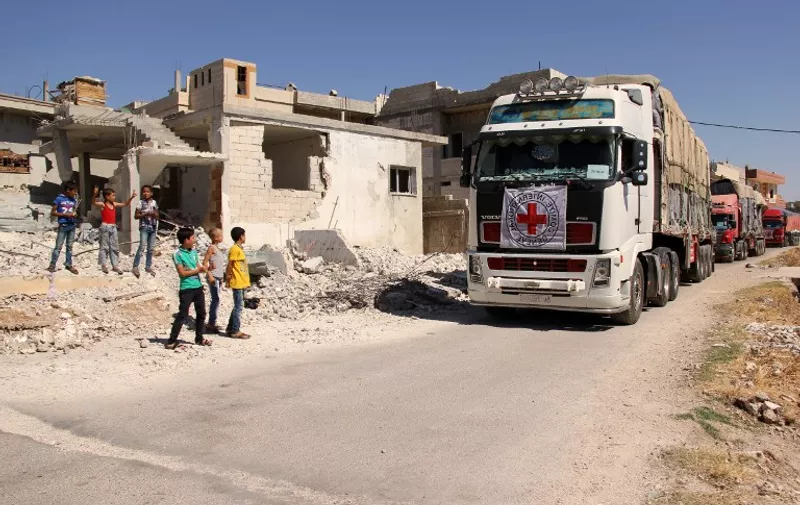 Syrian children stand on the side of a road watching a 48-truck convoy from the ICRC, SARC and UN driving through the Syrian rebel-held village of Teir Maalah, on the northern outskirts of Homs in central Syria, as it heads to the besieged town of Talbisseh on July 26, 2016.


The convoy, the second biggest convoy ever in Syria, entered Talbiseh, a besieged area in the Northern rural Homs, carriying food aid for 40,000 people and bulk food to support collective kitchens operating in the area, hygiene kits, mattresses, blankets and the kitchen sets. Since 2012, the town of Talbisseh has been besieged and heavily affected by ongoing fighting. / AFP PHOTO / MAHMOUD TAHA / The erroneous mention[s] appearing in the metadata of this photo by MAHMOUD TAHA has been modified in AFP systems in the following manner: [Teir Maalah] instead of [Talbisseh]. Please immediately remove the erroneous mention[s] from all your online services and delete it (them) from your servers. If you have been authorized by AFP to distribute it (them) to third parties, please ensure that the same actions are carried out by them. Failure to promptly comply with these instructions will entail liability on your part for any continued or post notification usage. Therefore we thank you very much for all your attention and prompt action. We are sorry for the inconvenience this notification may cause and remain at your disposal for any further information you may require.