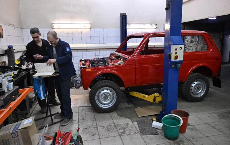Sergei Diogrik (R), the head of the Lada History Club, and his assistant Kamil restore an 80s Lada Niva, a legendary four-wheel drive car, in their garage in Tolyatti, also known as Togliatti, on March 31, 2022. - For generations the Russian city of Tolyatti has been synonomous with the maker of one of the country's best-known brands -- the Lada automobile. But with the West piling sanctions on Russia over its military action in Ukraine, Tolyatti and the workers of Avtovaz are bracing for tough times. (Photo by Yuri KADOBNOV / AFP)