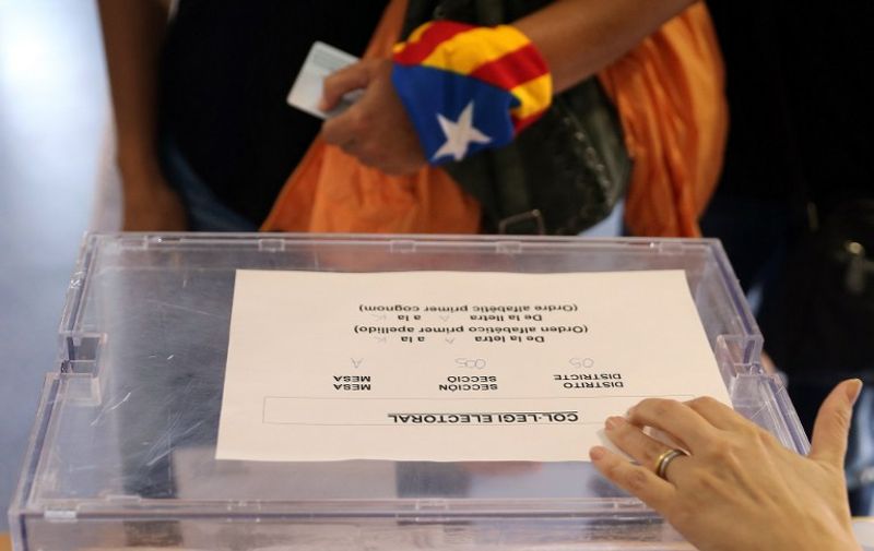 A woman with an "Estelada" (Catalan pro-independece flag) tied to her wrist waits for casting her ballot for the regional election at a polling station in Badalona on September 27, 2015. Catalans voted today in an election dubbed crucial for the future of Spain, with polls pointing to a win by separatists who vow to declare the region independent by 2017.  AFP PHOTO/ CESAR MANSO