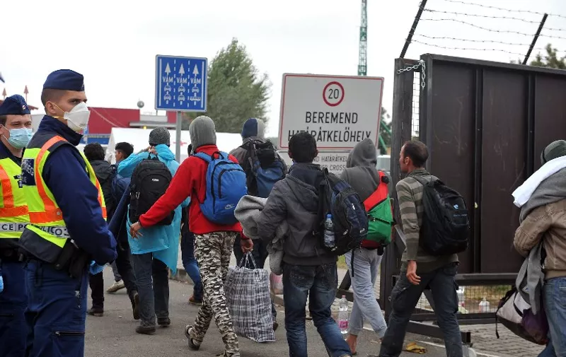 Migrants and refugees cross the Croatian-Hungarian border as Hungarian border police stand guard  from thevillage of Baranjsko Petrovo Selo, near the northeastern Croatian town of Beli Manastir, on September 25, 2015.  Nearly 60,000 migrants fleeing war and poverty in the Middle East and Africa have entered Croatia in recent days from its eastern neighbour Serbia, official figures showed on September 25. The influx started after Hungary sealed its border with Serbia earlier this month. AFP PHOTO / ELVIS BARUKCIC