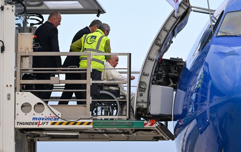 Pope Francis, seated on a wheelchair (C), is lifted on a platform to board a plane on November 3, 2022 at Rome's Fiumicino airport, prior to depart for a four-day trip to Bahrain. - Pope Francis visits Bahrain, home to the biggest Catholic church in the Arabian peninsula, during a November 3 to 6 trip, and will be the first pope to visit the Persian Gulf country. (Photo by Andreas SOLARO / AFP)