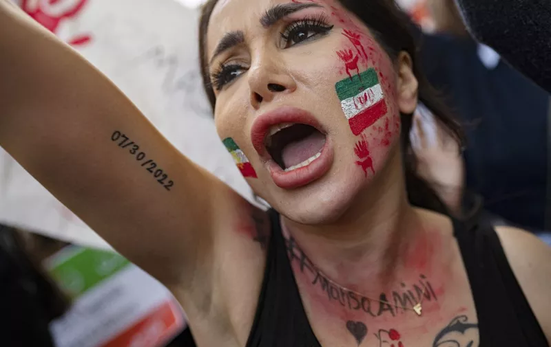 A demonstrator with an Iranian flag painted on her face, shouts slogans as she participates in a rally outside the Iranian consulate in Istanbul on October 17, 2022 after the death of Iranian Mahsa Amini, five weeks ago. - Amini, 22, died on September 16, 2022, three days after she was arrested by Iran's notorious morality police. (Photo by Yasin AKGUL / AFP)