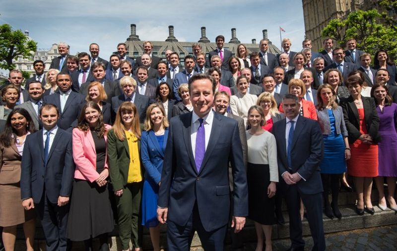 British Prime Minister David Cameron (C) poses for a group photo with newly-elected Conservative MPs at the Houses of Parliament in central London on May 11, 2015. British Prime Minister David Cameron unveiled his new cabinet on May 11 after an unexpected election victory that gave his Conservative party a narrow majority in parliament for the first time in nearly 20 years.  AFP PHOTO / POOL / STEFAN ROUSSEAU