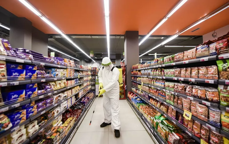 A worker disinfects the floor of a supermarket in Pristina on April 17, 2020, as a preventive measure against the spread of the new coronavirus, COVID-19. - Like most other cities across Europe Pristina is under lockdown measures to halt the spread of the virus. (Photo by Armend NIMANI / AFP)