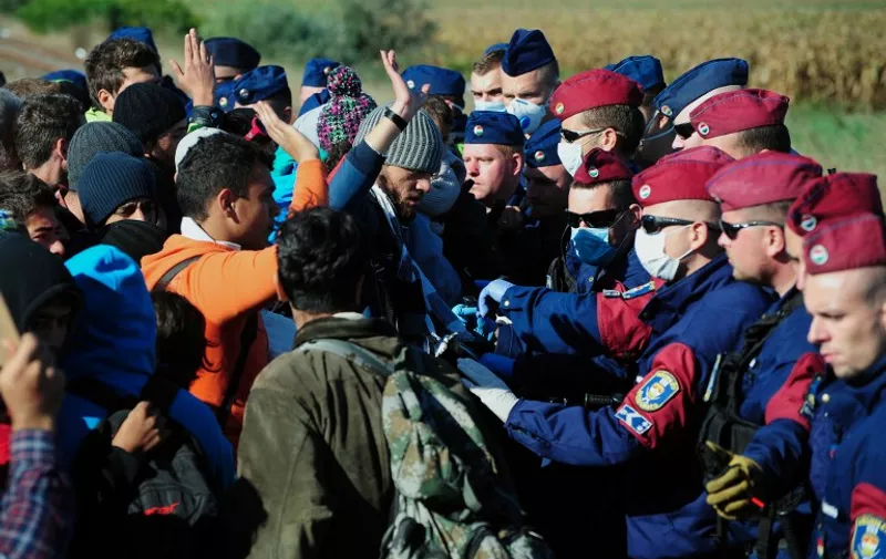 Migrants are controlled by police officers at the collection and registration local point for refugees at the Roszke village near the Hungarian-Serbian border on September 7, 2015. About 200 people broke out from this point after spending the night in open air as border camps are full. 
AFP PHOTO / CSABA SEGESVARI