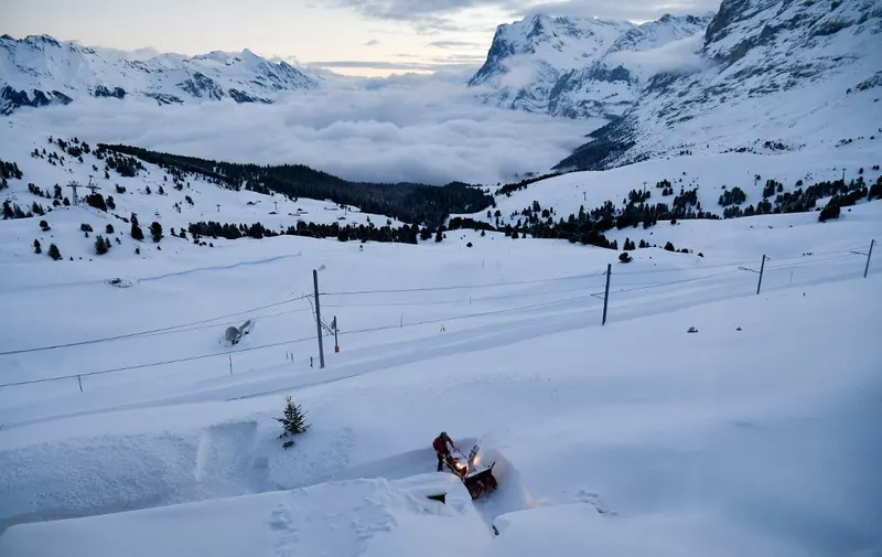 A man uses a machine to clear a path through the snow in the ski resort of Wengen in the Swiss Alps on January 18, 2019. (Photo by Lionel BONAVENTURE / AFP)