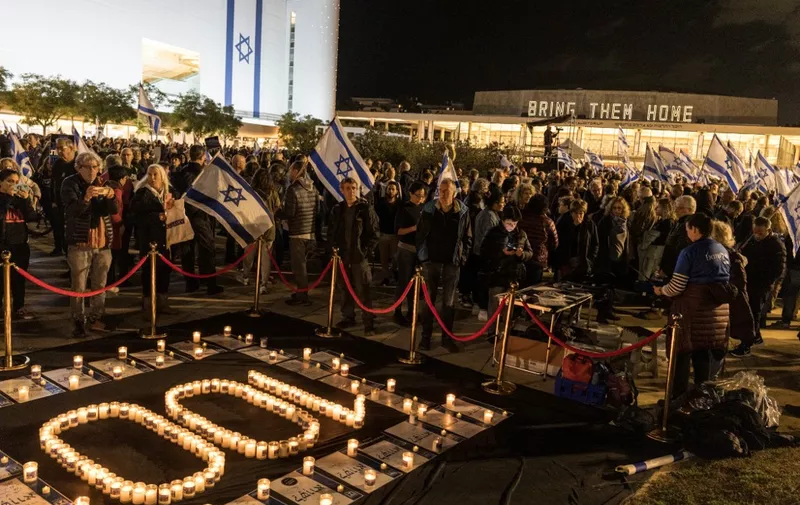 Israeli anti-government protesters gather around candles reading the number "100" during a demonstration in Tel Aviv, on January 13, 2024, after almost 100 days of war between Israel and the militant Hamas group in Gaza. (Photo by MARCO LONGARI / AFP)
