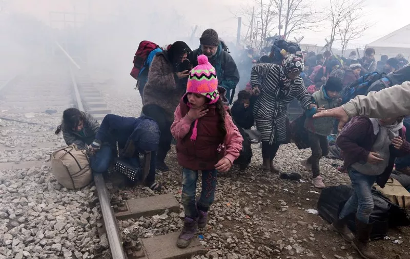 A child coughs as migrants and refugees run away after Macedonian police fired tear gas at hundreds of Iraqi and Syrian migrants who tried to break through the Greek border fence in Idomeni, on February 29, 2016.
Greek police said more than 6,000 people were massed at the border, in a buildup triggered by Austria and Balkan states capping the numbers of migrants entering their territory. / AFP / LOUISA GOULIAMAKI