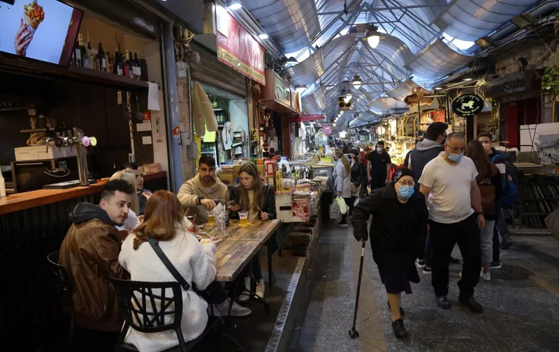 People eat at a restaurant in Jerusalem's main market after authorities reopened restaurants, bars and cafes to "green pass" holders (proof of having received a covid-19 vaccine), on March 11, 2021. (Photo by Emmanuel DUNAND / AFP)