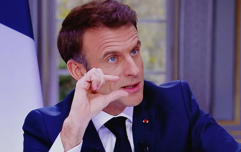French President Emmanuel Macron is seen on screen as he speaks during a TV interview from the Elysee Palace, in Paris, on March 22, 2023. French President is to make on March 22, 2023 his first public comments on the crisis sparked by his government forcing through a pensions overhaul, which has sparked violent protests and questions over his ability to bring about further change. (Photo by Ludovic MARIN / AFP)