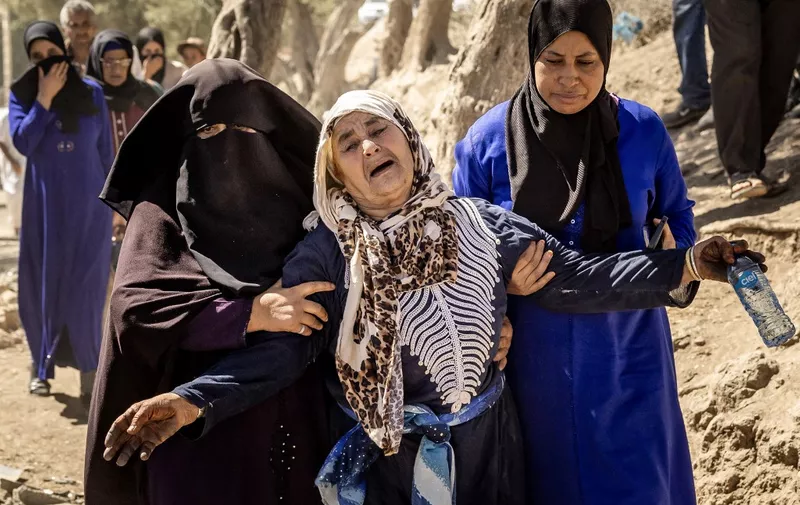A woman is helped as she reacts to the death of relatives in an earthquake in the mountain village of Tafeghaghte, southwest of Marrakesh, on September 10, 2023. Moroccans mourned the victims of a devastating earthquake that killed more than 2,000 people as the first foreign rescuers flew to help search the rubble of flattened villages. (Photo by FADEL SENNA / AFP)