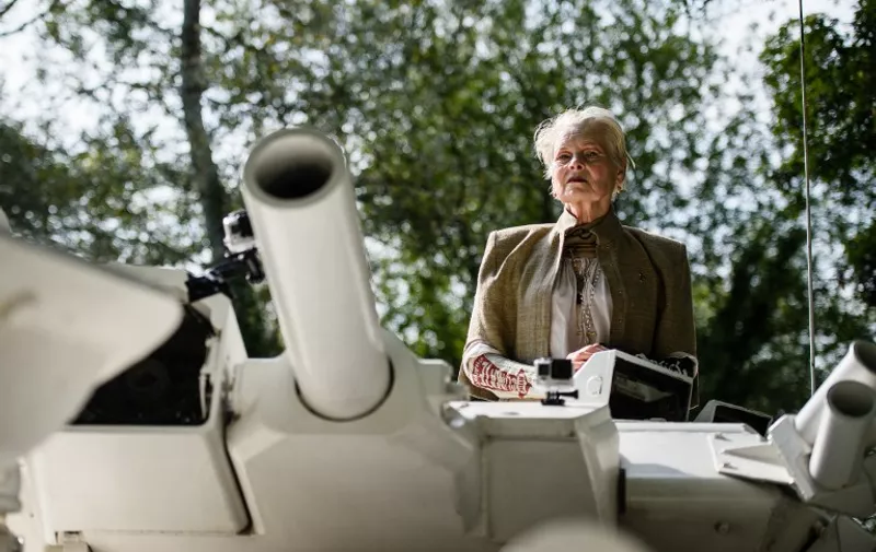 Fashion designer and environmental campaigner Vivienne Westwood rides on top of an armored personnel carrier (APC) towards the home of British Prime Minister David Cameron's home in Chadlington, Oxfordshire on September 11, 2015 to highlight the Government's plan to use hydraulic fracturing (fracking) to recover fossil fuels from the ground in regions of the north of England. The vehicle parked outside the prime minister's home before a group of protestors in gas masks led chants and held banners calling for the Government to change it's policy on the controversial plans.  AFP PHOTO / LEON NEAL