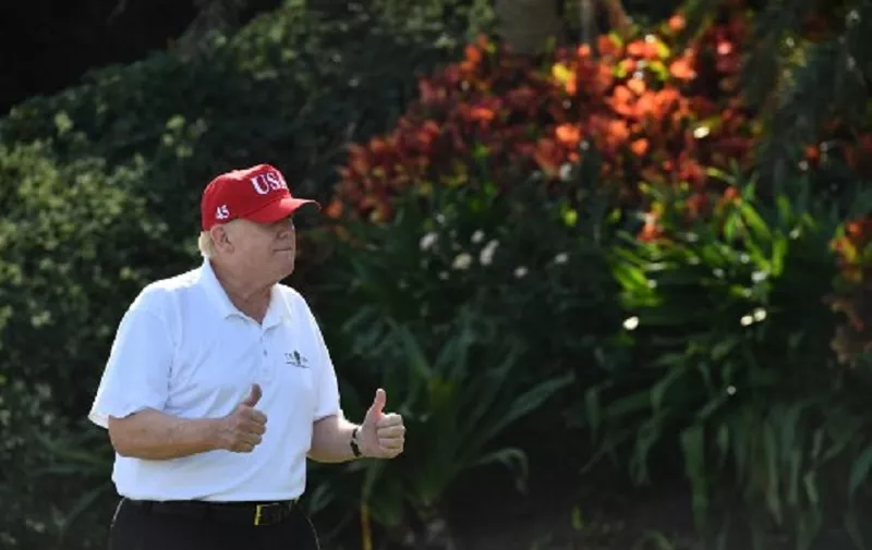 US President Donald Trump holds two thumbs up while meeting with service members of the United States Coast Guard to play golf at Trump International Golf Course in Mar-a-Lago, Florida on December 29, 2017.
The President invited members of the Coast Guard to play golf to thank them personally for their service of patrolling the waters near Palm Beach and Mar-a-Lago. / AFP PHOTO / Nicholas Kamm