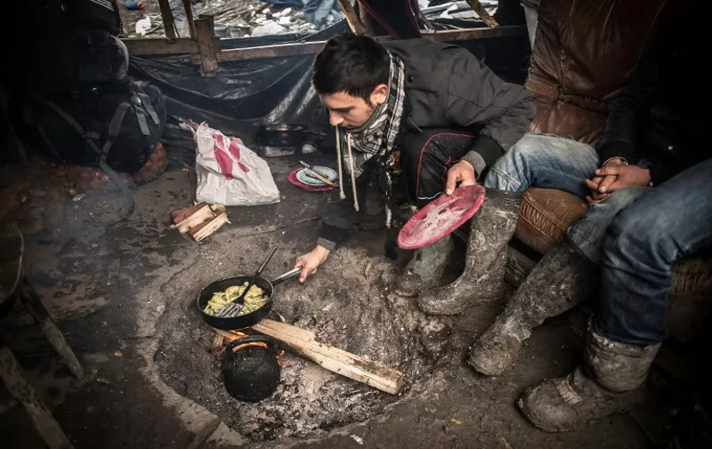 A migrant or refugee understood to be Iranian prepares food near tents on December 29, 2015 in a camp in Grande-Synthe.

On December 28, 2015 a migrant was found dead in the trailer of a truck in Grande-Synthe, the prefecture and firefighters said. Approximately 2,600 migrants live in a slum in a highway border near Grande-Synthe, in very precarious conditions. 4000-6000 exiles, according to sources, live in the "jungle" of Calais and since June 2015, 19 people died trying to reach England. / AFP / PHILIPPE HUGUEN