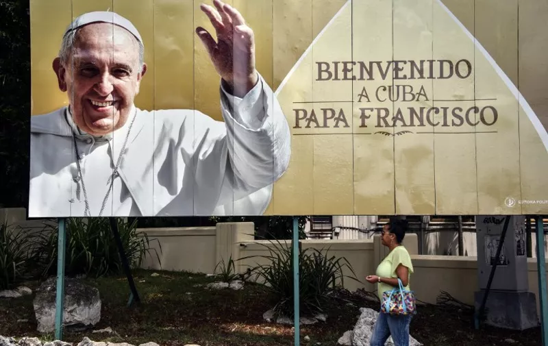 A woman walks near a poster of Pope Francis in a street of Havana, on September 16, 2015. The pope is visiting Cuba from September 19 to 22, the first stop on a trip that also will take him to the United States. In Cuba, he will visit Havana, the northeastern city of Holguin and Santiago de Cuba on the southeastern end of the island.            AFP PHOTO / MEHDI LEBOUACHERA