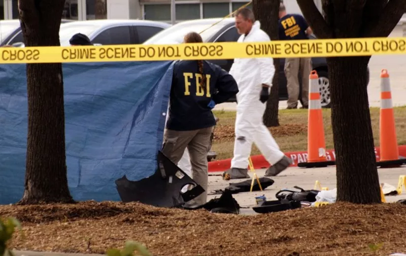 FBI agents view the area where the shooting suspects lay behind a blue covering, along with debris of a car that was blown up by police as a precaution, near the Curtis Culwell Center  on May 4, 2015 in Garland,Texas.  Police in Texas shot dead two gunmen outside a Prophet Mohammed cartoon contest put on by a group that has a history of sparking controversy with its statements on Islam.While no immediate claim of responsibility for the attack Sunday was made, similar depictions of the Prophet Mohammed prompted a shooting at French satirical weekly Charlie Hebdo in January that killed 12 people. Police said two men drove up to the conference center in Garland, Texas, "exited a vehicle and began shooting" at a security guard. "Garland Police officers engaged the gunmen, who were both shot and killed," the city of Garland said in a statement. AFP PHOTO/JARED L. CHRISTOPHER