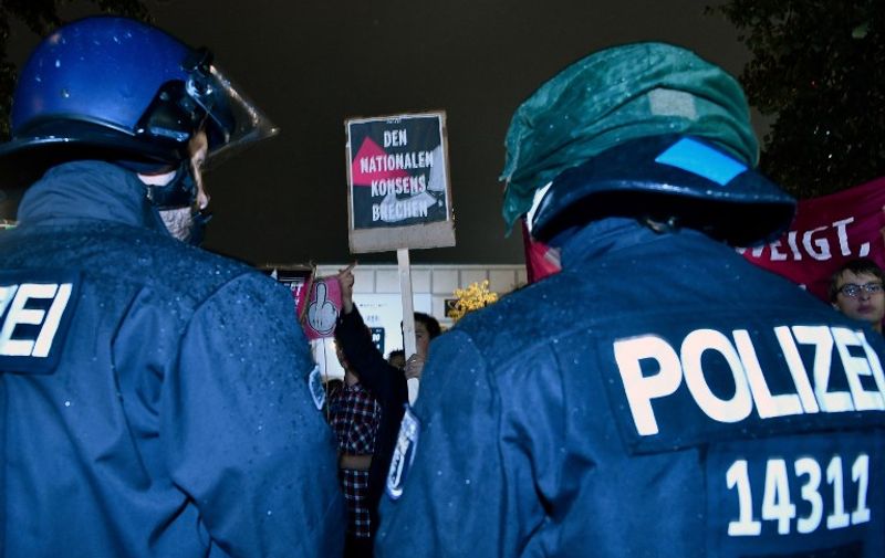 Riot Police stand by as protesters hold up sign which reads "Break the national consensus" during a protest outside an election night event of the Alternative for Germany (AfD) party in Berlin on September 24, 2017.
Germany voted in a general election expected to hand Chancellor Angela Merkel a fourth term, while the hard-right Alternative for Germany (AfD) party is predicted to win its first seats in the national parliament. / AFP PHOTO / John MACDOUGALL