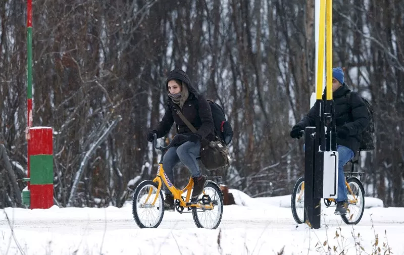 Two migrants on bikes cross the boarder between Norway and Russia in Storskog near Kirkenes in Northern Norway, on November 16, 2015. An increasingly popular route for migrants across Russia and into Norway has Oslo angered and worried as winter approaches, while commentators suspect Moscow is deliberately creating problems for its neighbour. Initially, the news that migrants were making a long detour through the Arctic had a whimsical quality to it: migrants have to make the last section of their journey by bicycle because Russian authorities don't let pedestrians cross the border and Norway considers it human trafficking to transport migrants in a vehicle.   AFP PHOTO / NTB SCANPIX  / CORNELIUS POPPE      +++ NORWAY OUT +++ / AFP / NTB SCANPIX / CORNELIUS POPPE