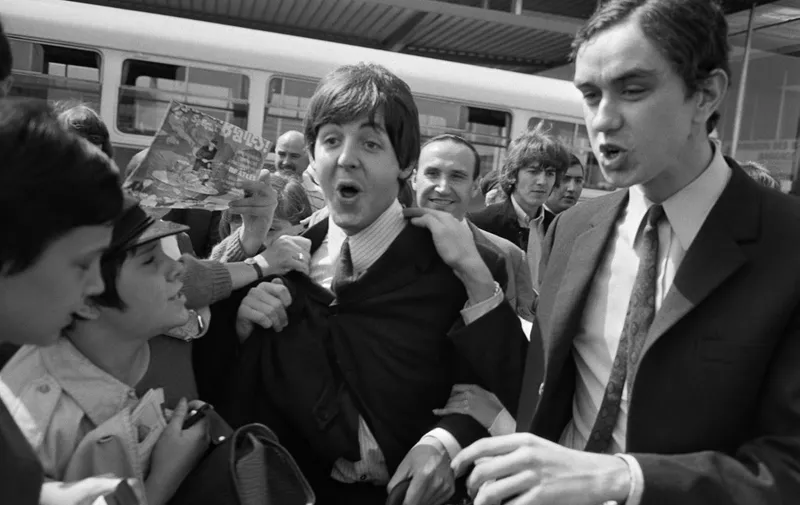 Fans surround the Beatles' members Paul McCartney (C) and George Harrison (2nd R) at their arrival at Orly airport on June 20, 1965, before their concert at the Palais des Sports the same evening. British band The Beatles made two performances at the Palais des Sports before a tour of France, Italy and Spain and then a tour in United States during summer 1965. It's the beginning of the Beatlemania, characterised by hysteria demonstrated by fans during concerts and tours. (Photo by AFP)