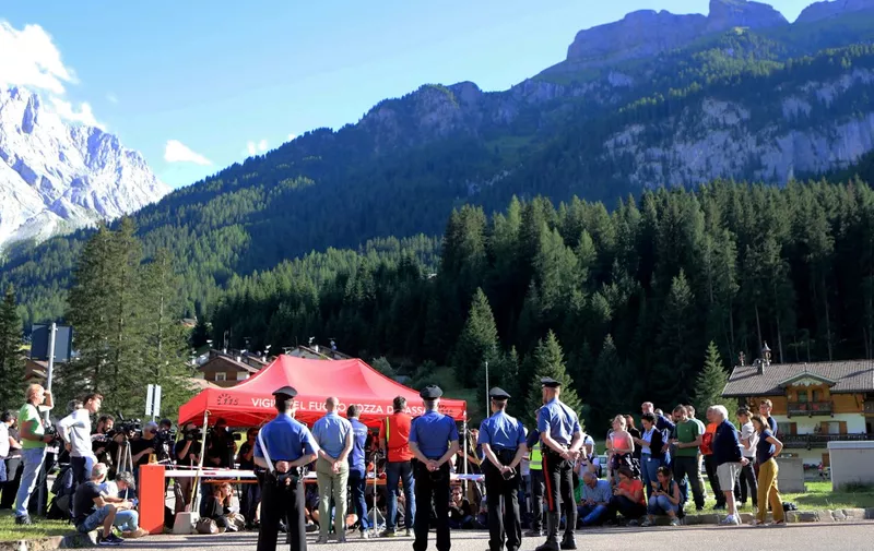 Police officers stand guard during a press point with rescue authorities in Canazei, north-eastern Italy, on July 5, 2022, two days after the collapse of the glacier of the Marmolada mountain. - The deadly collapse of an Italian glacier, causing an avalanche which killed at least seven people, is linked to climate change, Italy's Prime Minister said on July 4, 2022. (Photo by Pierre TEYSSOT / AFP)
