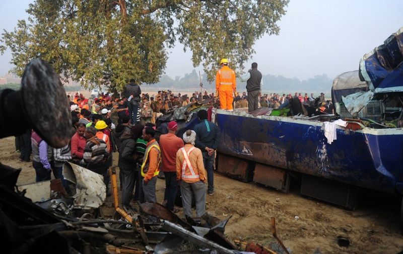 Rescue worker and onlookers stand near the wreckage of the train on the damaged tracks where a train derailed near Pukhrayan in India's Kanpur district on November 21, 2016.
Emergency workers raced to find any more survivors in the mangled wreckage of an Indian train that derailed on November 20, killing at least 120 people, in the worst disaster to hit the country's ageing rail network in recent years. / AFP PHOTO / SANJAY KANOJIA