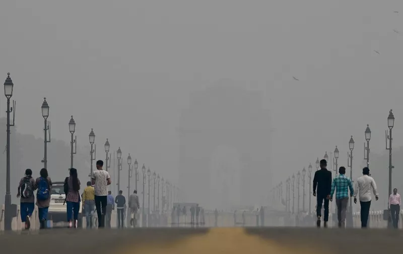 People walk along the Kartavya Path near India Gate amid heavy smog conditions in New Delhi on November 3, 2023. Schools were shut across India's capital on November 3 as a noxious grey smog engulfed the megacity and made life a misery for its 30 million inhabitants. (Photo by ARUN THAKUR / AFP)