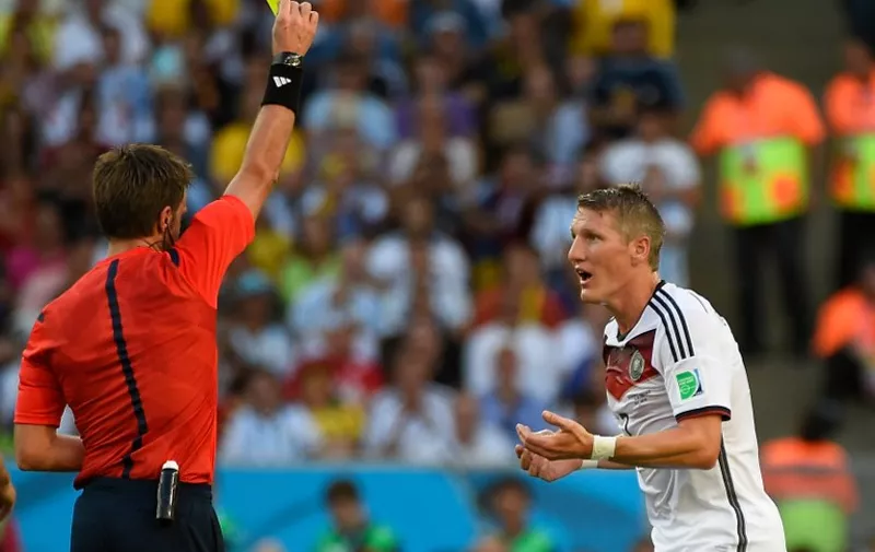 Germany's midfielder Bastian Schweinsteiger (R) shown a yellow card by Italian referee Nicola Rizzoli during the 2014 FIFA World Cup final football match between Germany and Argentina at the Maracana Stadium in Rio de Janeiro on July 13, 2014.  AFP PHOTO / ODD ANDERSEN / AFP / ODD ANDERSEN