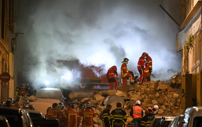 Rescue personnel work at the scene where a building collapsed in the southern French port city of Marseille early on April 9, 2023. - A building in the southern French port city of Marseille collapsed, police told AFP early on April 9, though it was unclear whether there were any victims. (Photo by NICOLAS TUCAT / AFP)