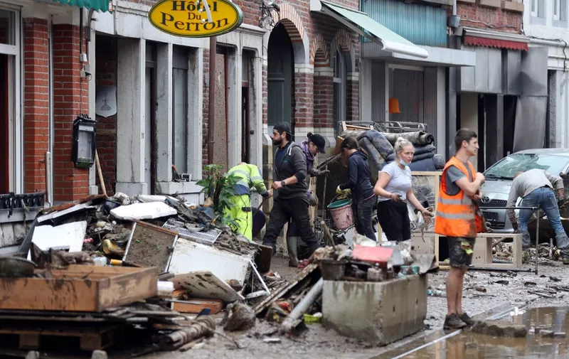 Residents and workers clear up a street after the floods caused major damage in Theux, near Liege, on July 16, 2021. - The death toll in Belgium jumped to 23 with more than 21,000 people left without electricity in one region. (Photo by François WALSCHAERTS / AFP)