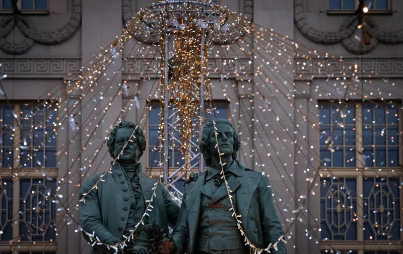 26 December 2023, Thuringia, Weimar: The Goethe-Schiller monument in front of the Deutsches Nationaltheater (DNT) in Weimar's city center is framed by a glowing string of lights. The bronze double statue of the two poets Johann Wolfgang von Goethe and Friedrich Schiller (designed by sculptor Ernst Rietschel) stands on Theaterplatz until 7 January 2024 at the edge of an ice rink for ice skating. Photo: Soeren Stache/dpa (Photo by SOEREN STACHE / DPA / dpa Picture-Alliance via AFP)