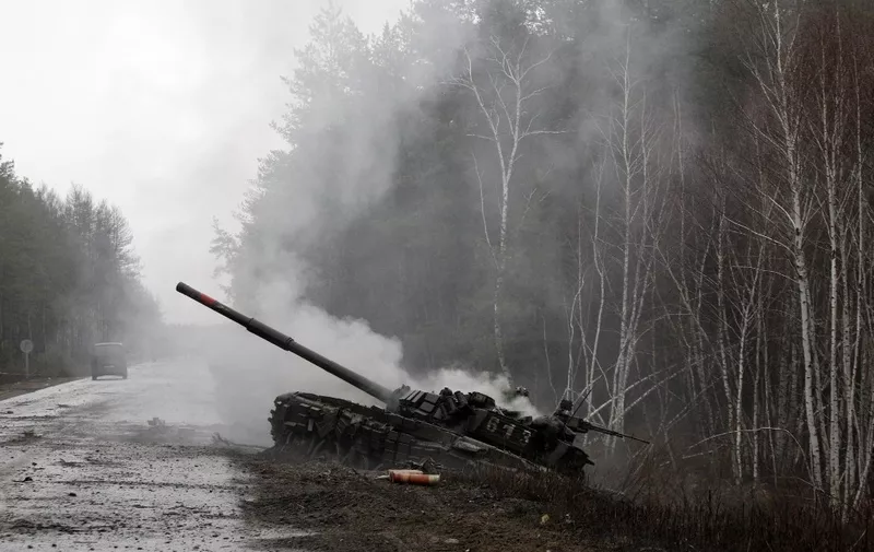 Smoke rises from a Russian tank destroyed by the Ukrainian forces on the side of a road in Lugansk region on February 26, 2022. - Russia on February 26 ordered its troops to advance in Ukraine "from all directions" as the Ukrainian capital Kyiv imposed a blanket curfew and officials reported 198 civilian deaths. (Photo by Anatolii Stepanov / AFP)