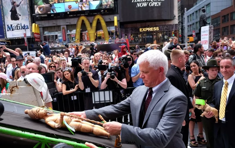 A participant places a confiscated artwork on a crash-machine during a ceremony at the Times Square in New York on June 19, 2015. The US Fish and Wildlife Service destroyed more than one ton of confiscated illegal ivory in a public show at the Times Square to raise awareness of the elephant poaching and wildlife trafficking crisis. AFP PHOTO/JEWEL SAMAD